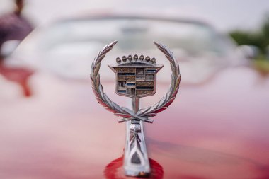 limbazi, Letonya, 29 Haziran 2024 - Arkaplanı bulanık bir Cadillac kaput süslemesi. Amblem parlak kırmızı bir arabanın kaputunda duruyor. Bazı kopyalama alanı.