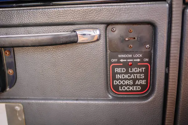 stock image limbazi, Latvia, June 29, 2024 - Close-up of a car door panel showing a window lock switch and a sign indicating a red light for locked doors. Some copy space.