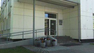 Balvi, Letonya - 28 Mayıs 2024 - Balvi 'de rampası, merdivenleri ve saksısı olan modern bir binanın giriş videosu.