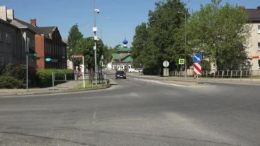 Balvi, Letonya - 28 Mayıs 2024 - Güneşli bir günde Letonya 'nın Balvi kentinde arabaları, yayaları ve binaları olan bir caddenin videosu. Arka planda mavi kubbeli bir kilise görülebilir. Videosu..