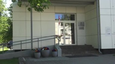 Balvi, Letonya - 28 Mayıs 2024 - Rampası, saksısı ve duvarda duran bir çocuğun olduğu bir binanın girişinin videosu. Penceredeki yansımalar. Boşluğu kopyala.