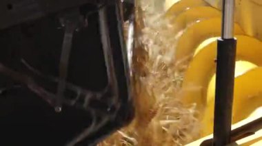  Hasat makinesinin arpa işleme mekanizmasının yakın plan görüntüsü, sarı dönen parçaları ve hareket eden tahılları gösteriyor.