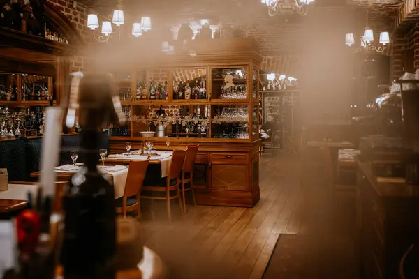 stock image Riga, Latvia March 20, 2024 - Elegant restaurant interior with wooden furniture, a wine cabinet, and neatly set tables, featuring a cozy and inviting ambiance.