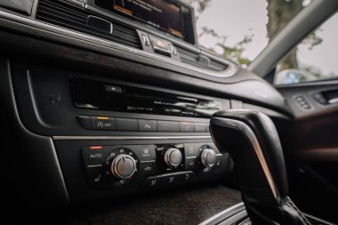 Valmiera, Letonya - 1 Ağustos 2024 - İklim kontrol kadranları, medya sistemi ve vites değiştiricisinin yer aldığı, iç tasarım ve işlevselliği gösteren lüks bir arabanın merkez konsolunun yakın çekimi.