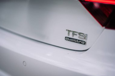 Valmiera, Letonya - 1 Ağustos 2024 - Beyaz bir Audi arabanın arkasında TFSI Quattro rozetine yakın plan, markalaşma ve tasarım detaylarını vurguluyor.
