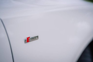 Valmiera, Letonya - 1 Ağustos 2024 - Beyaz bir arabanın kenarındaki Audi S Line rozetine yakın çekim, amblemin tasarımı pürüzsüz kaportayla karşılaşıyor.