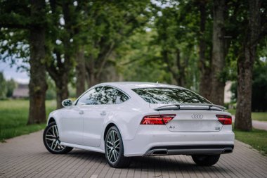 Valmiera, Letonya - 1 Ağustos 2024 - Beyaz bir Audi A7 arka taraftaki ağaçlık bir sokağa park edilmiştir..