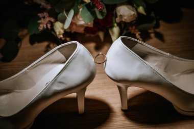 Cesis, Letonya - 12 Temmuz 2024 - Aralarında dengeli elmas bir nişan yüzüğü olan iki yüksek topuklu ayakkabıya yakın çekim.