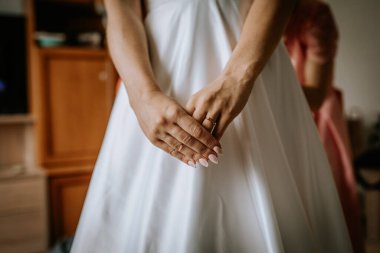 Cesis, Letonya - 12 Temmuz 2024 - Gelinin gelinliğinin üzerinde uzanan, nişan yüzüğünü ve manikürlü tırnaklarını vurgulayan, zarif ve huzurlu bir an yaratan bir gelinin yakın çekimi.