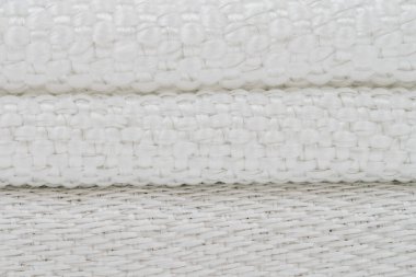 Üç üst üste dizilmiş fiberglas kumaş, görünür metal ipliklerle örülmüş, farklı dokular ve karmaşık dokuma desenleri vurgulanıyor..