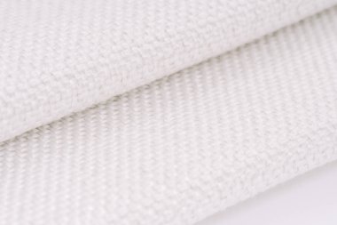 Görünür metal ipliklerle örülmüş beyaz dokuma kumaş, katlanmış kısımları ve karmaşık dokuyu gösteriyor. Resim dokuma desenini vurgular.