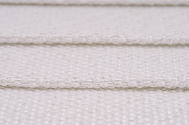 Görünür metal ipliklerle örülmüş beyaz dokuma kumaş, katlanmış kısımları ve karmaşık dokuyu gösteriyor. Resim dokuma desenini vurgular.