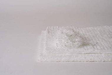 Üzerinde karmaşık fiberglas şeritler olan beyaz fiberglas paspaslar yakın plan, düz arkaplan üzerine kurulmuş. Görüntü materyalin dokusunu ve detaylarını gösterir..