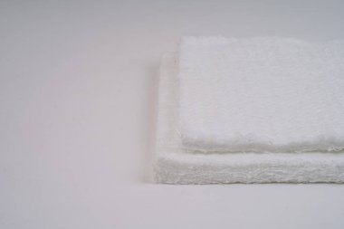 Beyaz arka planda fibröz dokuya sahip iki adet fiberglas hasırın yakın çekimi. Resim kabataslak yüzeyi ve katmanlı yapıyı gösterir.