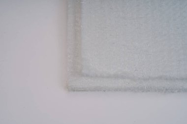 Beyaz arkaplanda üst üste binen fiberglas paspasların yakın çekimi, lifli dokuyu ve ayrıntıları gösterir.