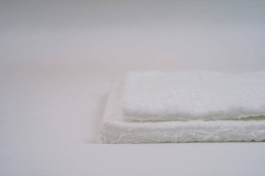 Beyaz arka planda fibröz dokuya sahip iki adet fiberglas hasırın yakın çekimi. Resim kabataslak yüzeyi ve katmanlı yapıyı gösterir.