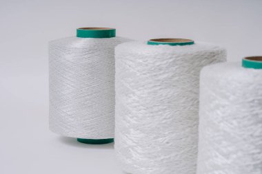 Farklı dokularda üç adet beyaz fiberglas ipliğin yakın plan görüntüsü, çapraz hizalanmış, desenlerini ve detaylarını gösteriyor.