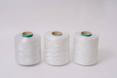 Üç adet beyaz fiberglas iplik makarası düz bir arka planda sıralanmış, farklı doku ve kalınlıkları sergiliyor..