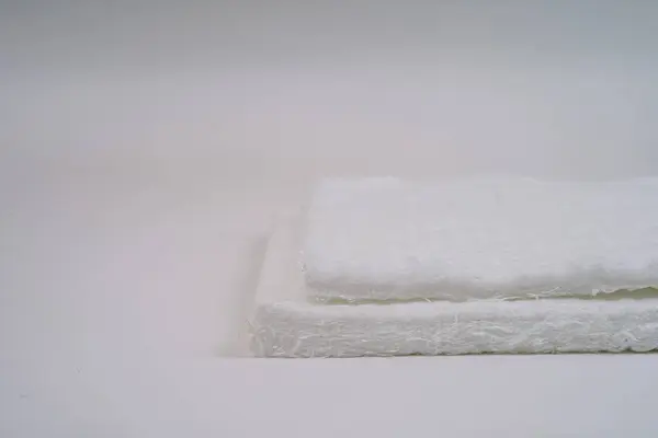 stock image Close-up of two stacked fiberglass mats with a fibrous texture on a white background. The image shows the rough surface and layered structure.