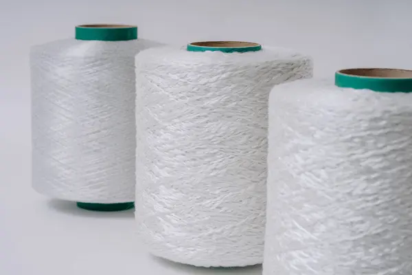 stock image Close-up of three spools of white fiberglass yarn arranged in a row, showcasing different textures and details, with a simple background.