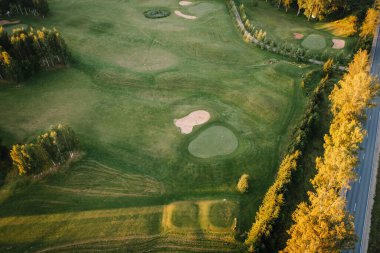 Valmiera, Letonya - 15 Ağustos 2024 - Yeşiller, sığınaklar ve güneş doğarken yakalanan ağaçlarla çevrili bir golf sahasının havadan görünüşü. Boşluğu kopyala.