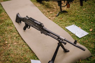 Valmiera, Latvia - August 17, 2024 - Summer festival. A machine gun is displayed on a mat in an outdoor setting, likely part of a military or firearm exhibition. The weapon is equipped with a bipod. clipart