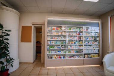 Ilukste, Letonya - 10 Eylül 2024 - Eczanede çeşitli ilaç ve sağlık ürünleri ile kaplanmış raflar bulunuyor, modern bir tasarım ve dost bir alışveriş deneyimi için doğal ışıklandırma ile tamamlanmış.