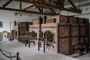 Munich, Germany - September 13, 2024 - Crematorium ovens at Dachau concentration camp, a grim reminder of Holocaust atrocities, with a memorial wreath placed nearby. clipart