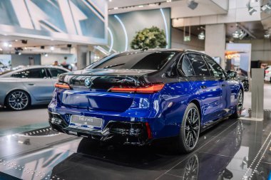 Münih, Almanya - 13 Eylül 2024 - Görüntü, vitrindeki mavi bir BMW i7 M70 'in parlak tasarımı, arka lambaları ve modern özelliklerini göstermektedir..