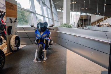 Münih, Almanya - 13 Eylül 2024 - Mavi bir BMW R 1250 RS motosiklet kapalı bir galeride sergileniyor, aksesuarları yakınlarda sergileniyor..