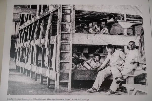 stock image Munich, Germany - September 13, 2024 - Historical photo of prisoners inside Dachau concentration camp, resting in overcrowded wooden bunk beds during WWII.