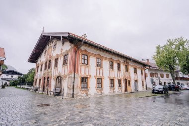 Oberammergau, Almanya - 14 Eylül 2024 - Avrupa 'nın tuhaf bir şehir meydanında, yağmurlu bir günde ayrıntılı freskleri ve süslü camları olan tarihi bina.