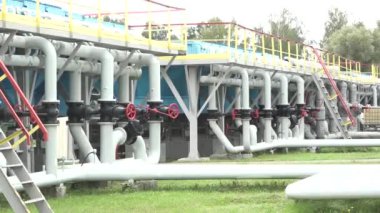 Sigulda, Letonya - 10 Ağustos 2024 - Sanayi boru sistemi, kırmızı valfler ve birçok boru hattı sıralanmış, büyük bir tesisin parçası, çimlerin üzerinde..