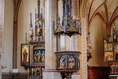 Bavyera, Almanya - 14 Eylül 2024 - Süslü heykeller, altın ayrıntılar ve Gotik mimari unsurları vurgulayan dekoratif bir kürsü ile karışık kilise içi.