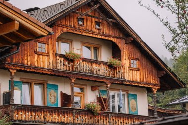 Bavyera, Almanya - 14 Eylül 2024 - Dekoratif balkonları ve çiçek kutuları olan geleneksel ahşap bir dağ evi, tipik Bavyera mimarisi, arka planda yeşillik.