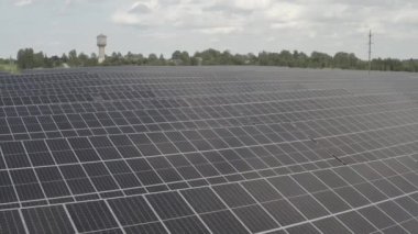 Güneş panelleri, parçalı bulutlu bir gökyüzünün altında geniş bir güneş çiftliği boyunca uzanıyor ve temiz enerji üretiyor. Yüksek kalitede s-log ve 4K ile yakalandı.