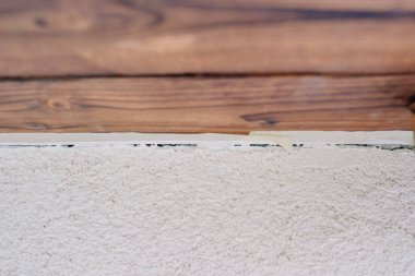 Üzerinde ahşap paneller olan yeni kaplanmış bir duvarın yakın çekimi, yenileme projesi sırasında malzemeler arasındaki temiz kenarı gösteriyor.