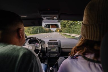 Bavyera, Almanya - 15 Eylül 2024 - Yoldaki bir arabanın arka koltuğundan iki kişiyi ve ilerideki yolu gösteren bir manzara, ağaçlar ve açık gökyüzü.