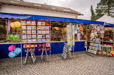 Bavaria, Germany - September 15, 2024 - A colorful market stall in Bavaria displaying toys, books, and games, with plush toys and childrens items hanging from racks outside clipart