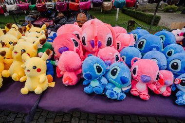 Bavyera, Almanya - 15 Eylül 2024 - Pikachu ve diğer karakterlerin de dahil olduğu renkli oyuncak sergisi, arka planda çantalarla birlikte Bavyera 'daki bir açık hava pazarında.