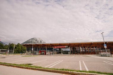 Tirol, Avusturya - 15 Eylül 2024 - Modern ahşap cepheli bir Eurospar süpermarketi, bir dağ zeminine karşı kurulmuş. Park yeri bulutlu bir gökyüzünün altında çoğunlukla boş..