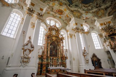 Bavyera, Almanya - 15 Eylül 2024 - Wieskirche 'deki karmaşık barok sunak ve heykeller, yüksek kemerli camları ve ayrıntılı altın süslemeleri olan UNESCO miras kilisesi.