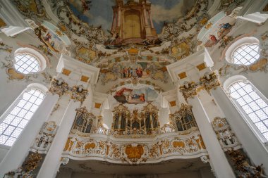 Bavyera, Almanya - 15 Eylül 2024 - Wieskirche 'de detaylı freskler ve altın süslemelerle süslü barok org dairesi, yüksek pencereler ve karmaşık mimari tasarımlar.