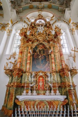 Bavyera, Almanya - 15 Eylül 2024 - Karmaşık altın detaylarıyla, heykellerle ve dini resimlerle süslü bir barok sunağı, parlak, büyük bir kilisenin içinde.