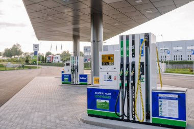 Valmiera, Letonya - 8 Ağustos 2024 - AdBlue ve EVO Diesel de dahil olmak üzere yakıt pompaları olan, temiz, ferah bir arsada, park yeri ve çevresindeki binaların yer aldığı modern bir benzin istasyonu.