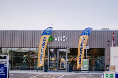 Valmiera, Letonya - 8 Ağustos 2024 - Geniş pencereli, tanıtım bayraklı ve tabelalı bir VIRSI mağazasının dışı açık bir günde fotoğraflandı.