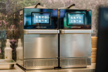 Valmiera, Letonya - 8 Ağustos 2024 - Fast food hazırlamak için kullanılan profesyonel mutfak ortamında dijital ekranları olan iki Merrychef ticari fırını.