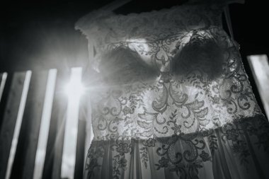 Valmiera, Letonya - 24 Ağustos 2024 - Güneş ışığının aktığı, karmaşık desenleri vurgulayan ve dramatik, klasik bir etki yaratan dantelli bir gelinliğin siyah ve beyaz yakın çekimi.