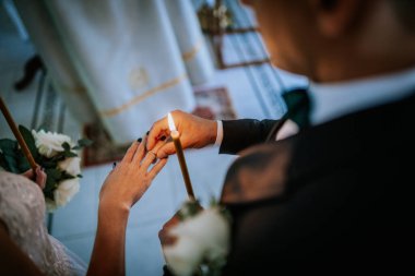 Valmiera, Letonya - 24 Ağustos 2024 Damadın düğün töreninde damat parmağına bir yüzük takması, aşk ve bağlılığı simgeleyen mum ve çiçeklerle