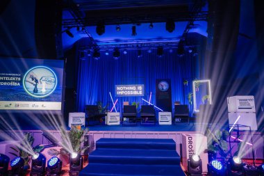 Valmiera, Letonya - 18 Ekim 2024 - yapay zeka konferansı. Neon işaretleri, bitkiler ve sunum içeriğini gösteren geniş bir ekran içeren bir konferans için parlak bir sahne..